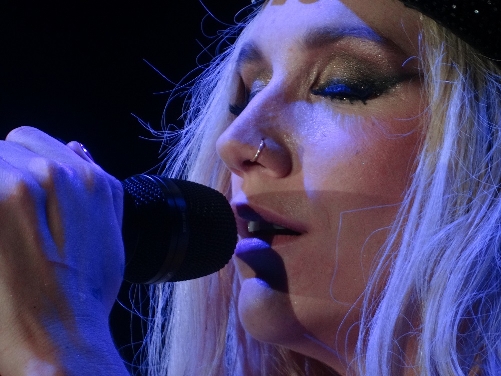 Close-up of Kesha singing into a microphone.