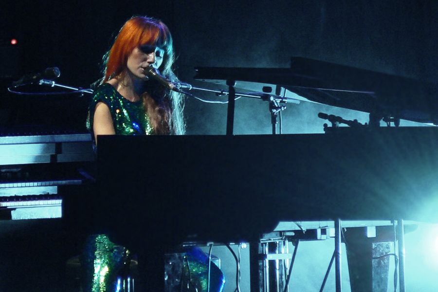 Tori Amos sitting behind a grand piano performing