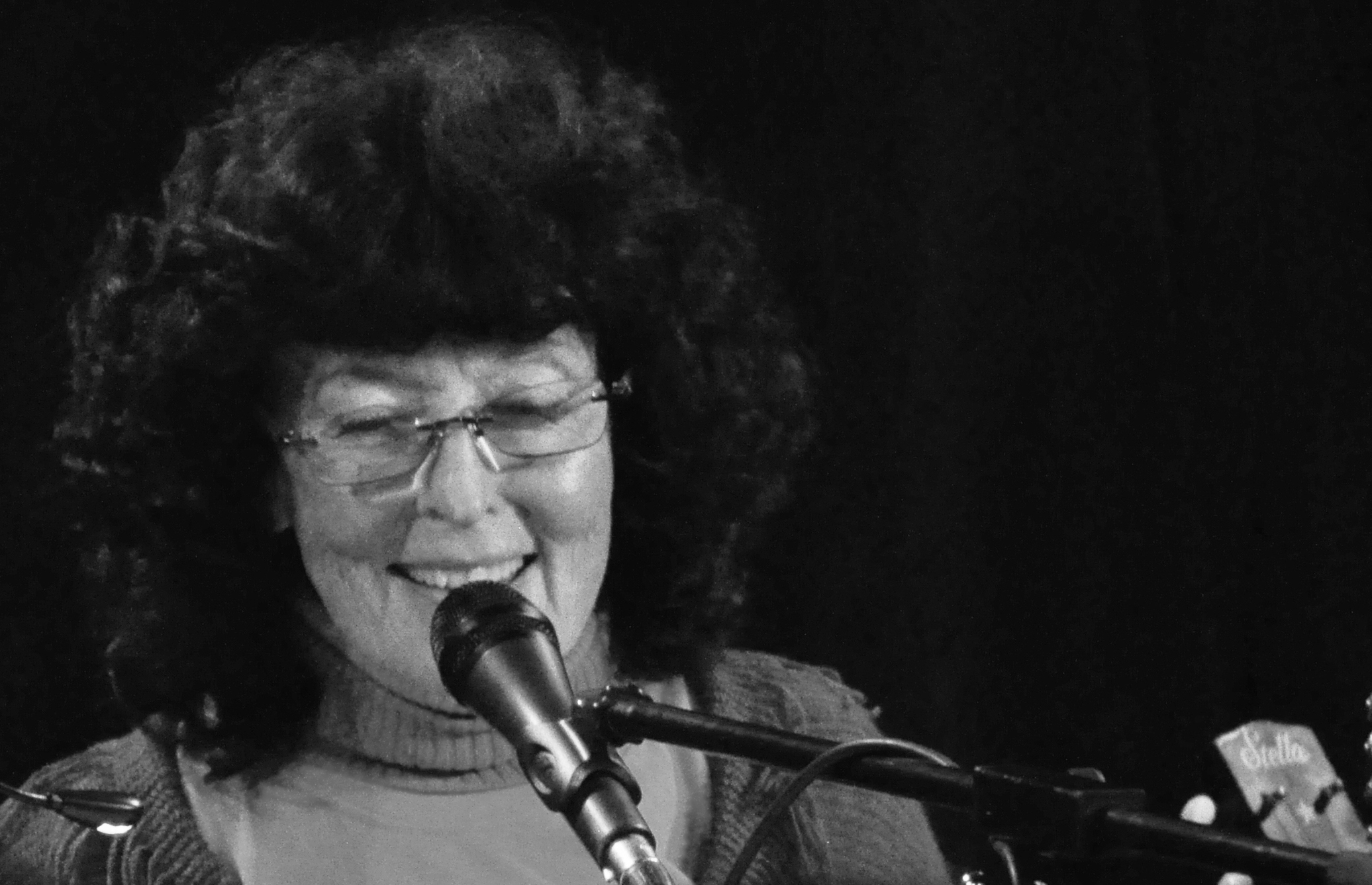 Black and white photo of Linda Perhacs speaking or singing into a microphone.